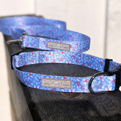 Light blue winter-themed Lucky Love Dog collar and leash with snowflake and berry pattern displayed on a wooden surface.