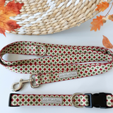 Dog collar and leash with green holiday pattern displayed on a table with fall decor.