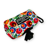 Floral dog waste bag holder with Lucky Love Dog Austin branding, featuring a convenient clip and attached waste bags.
